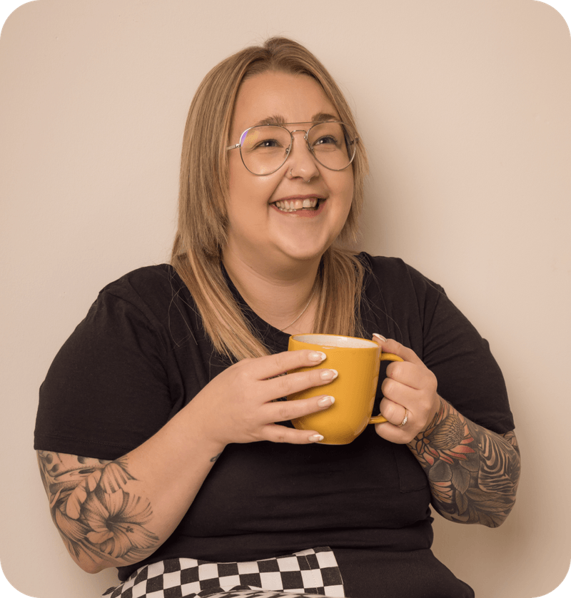 Gemma Helyer smiling at the camera, holding a yellow mug of tea.